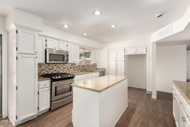 kitchen featuring light stone counters, white cabinetry, stainless steel appliances, and a kitchen island