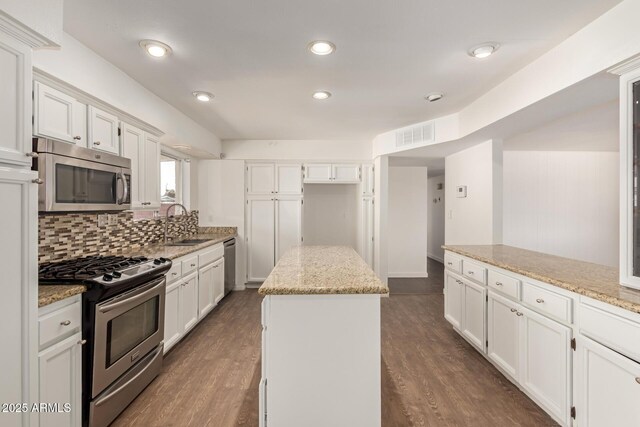 kitchen with light stone countertops, a kitchen island, white cabinetry, and appliances with stainless steel finishes