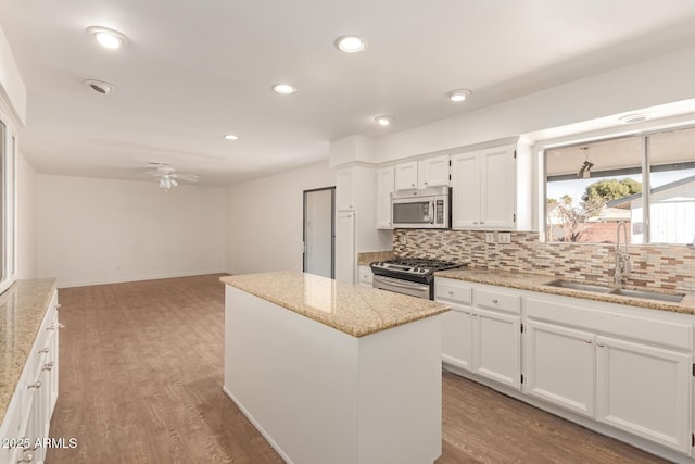 kitchen featuring appliances with stainless steel finishes, a center island, white cabinetry, tasteful backsplash, and sink