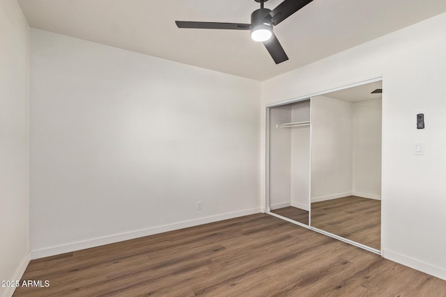 unfurnished bedroom featuring dark wood-type flooring, ceiling fan, and a closet