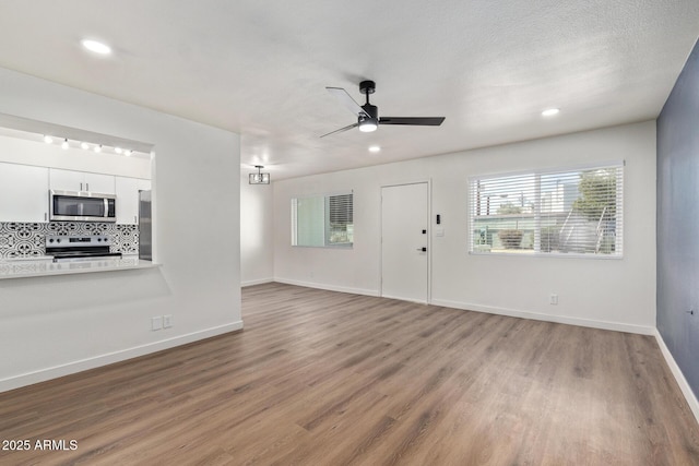 unfurnished living room with wood-type flooring, a textured ceiling, and ceiling fan