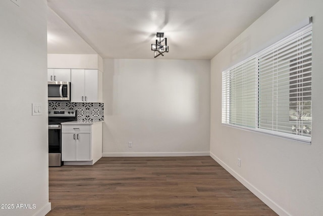 kitchen featuring tasteful backsplash, dark hardwood / wood-style floors, white cabinets, and appliances with stainless steel finishes