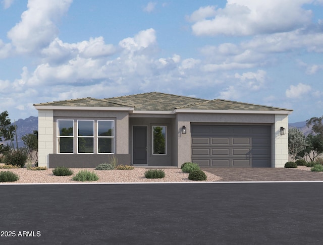 prairie-style home featuring a garage, a mountain view, stucco siding, and driveway