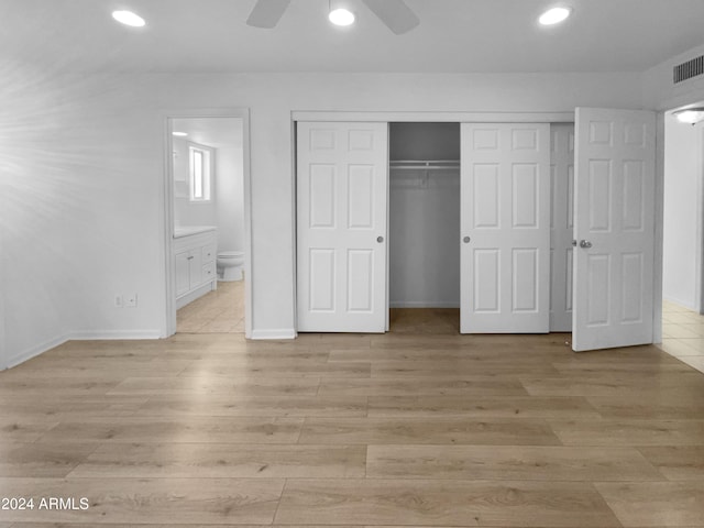 unfurnished bedroom featuring a closet, light hardwood / wood-style flooring, ensuite bath, and ceiling fan