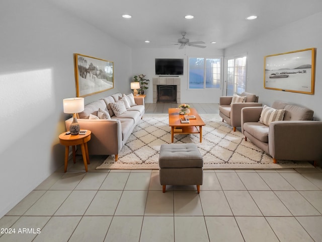 living room with a tiled fireplace, ceiling fan, and light tile patterned flooring