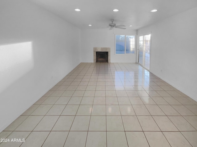 unfurnished living room with ceiling fan, a fireplace, and light tile patterned floors