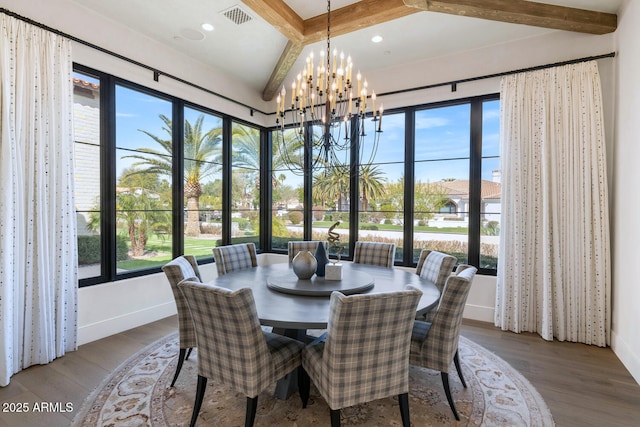 dining space featuring wood-type flooring, plenty of natural light, a notable chandelier, and beam ceiling