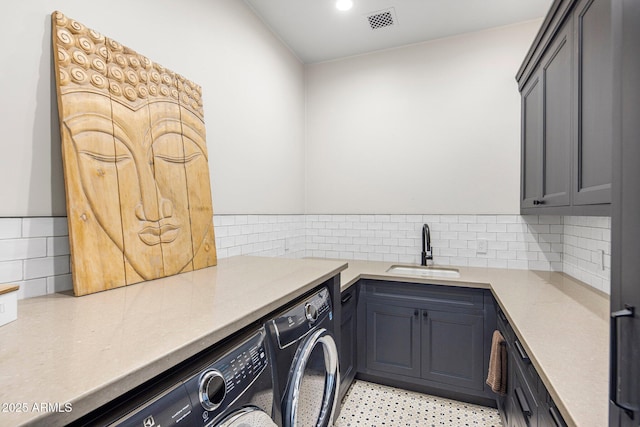 clothes washing area with cabinets, separate washer and dryer, and sink