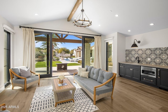 living room with lofted ceiling with beams, hardwood / wood-style floors, a notable chandelier, and indoor wet bar