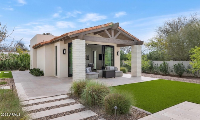 rear view of property with an outdoor structure, a patio, and a lawn