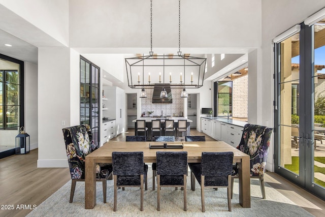 dining area with a high ceiling, plenty of natural light, and light wood-type flooring