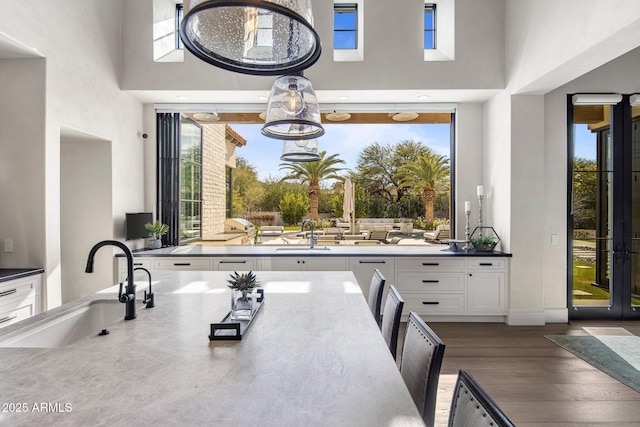 kitchen featuring dark hardwood / wood-style flooring, a wealth of natural light, sink, and white cabinets