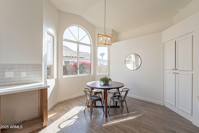 dining space with vaulted ceiling, a chandelier, and hardwood / wood-style floors