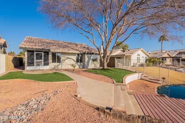 rear view of property featuring a sunroom, a patio area, and a lawn