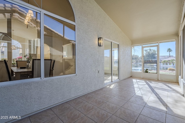 unfurnished sunroom with lofted ceiling and a water view