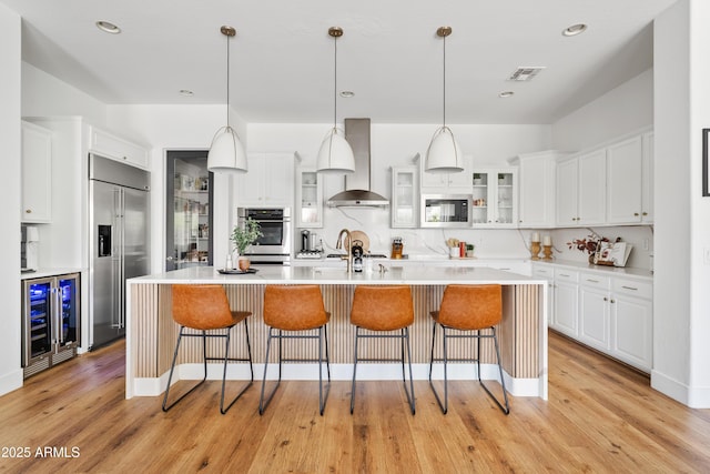 1500 E Sagittarius Pl, Chandler, AZ 85249 - kitchen featuring wall chimney exhaust hood, beverage cooler, built in appliances, light countertops, and white cabinetry
