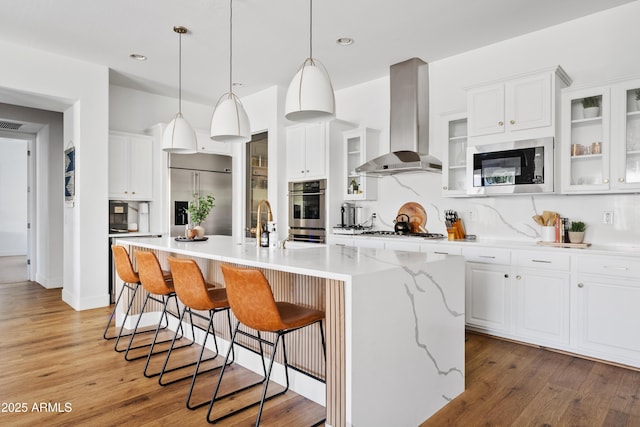 1500 E Sagittarius Pl, Chandler, AZ 85249 - kitchen featuring wall chimney range hood, built in appliances, decorative backsplash, an island with sink, and recessed lighting