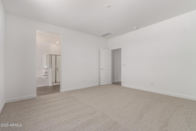 unfurnished bedroom with carpet flooring, baseboards, and ensuite bathroom