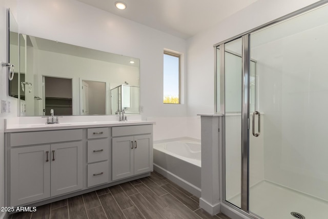 full bathroom with a stall shower, a bath, double vanity, recessed lighting, and wood finish floors