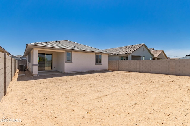 rear view of property featuring a tile roof, central AC, stucco siding, and a fenced backyard