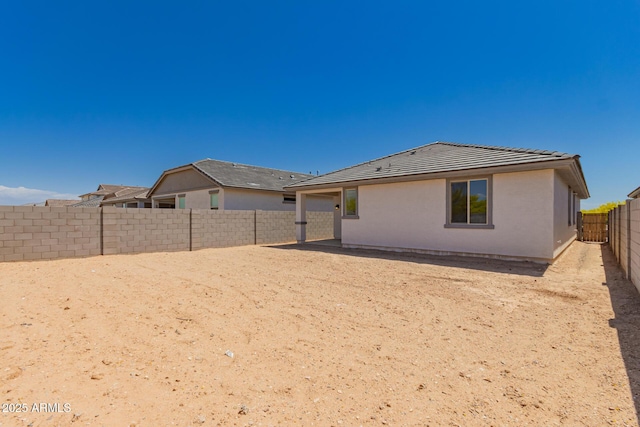 back of property with a tiled roof, a fenced backyard, and stucco siding
