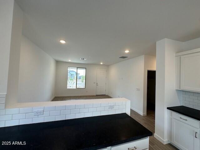 kitchen featuring dark countertops, wood finished floors, white cabinetry, tasteful backsplash, and recessed lighting