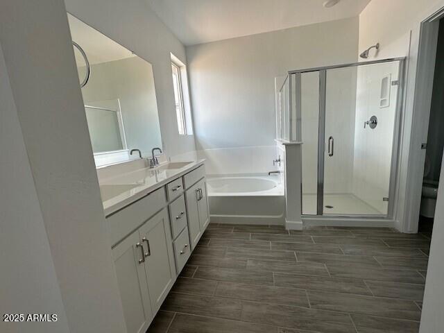 bathroom featuring a garden tub, a stall shower, double vanity, and wood tiled floors