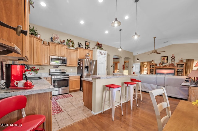 kitchen featuring appliances with stainless steel finishes, ceiling fan, pendant lighting, a center island, and lofted ceiling