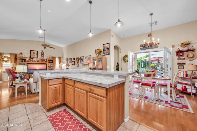 kitchen with light hardwood / wood-style flooring, ceiling fan with notable chandelier, hanging light fixtures, and lofted ceiling