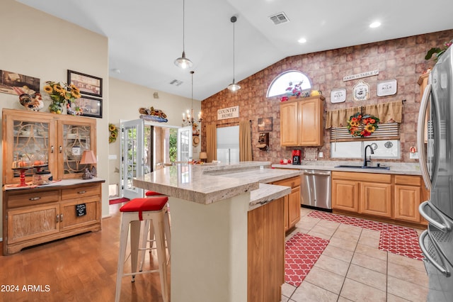 kitchen featuring a center island, lofted ceiling, a kitchen breakfast bar, sink, and appliances with stainless steel finishes