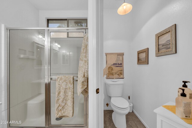 bathroom featuring tile patterned floors, toilet, and a shower with shower door