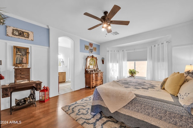 bedroom featuring connected bathroom, ceiling fan, crown molding, and wood-type flooring