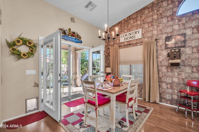 dining room with hardwood / wood-style flooring, high vaulted ceiling, and a notable chandelier