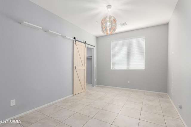 unfurnished bedroom featuring a barn door and light tile patterned flooring