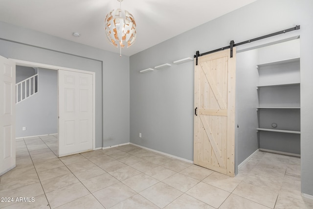 unfurnished bedroom with light tile patterned floors, a barn door, and a closet