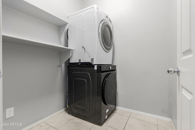 laundry room with stacked washer / dryer and light tile patterned floors