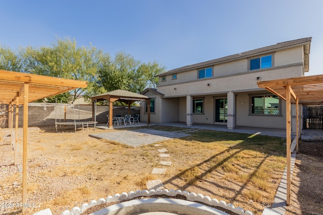 back of property with a gazebo, a pergola, a trampoline, and a patio area