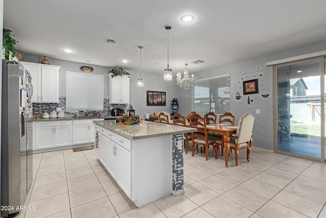 kitchen with stainless steel fridge, plenty of natural light, a kitchen island, and white cabinetry