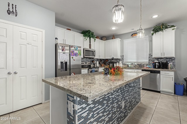 kitchen featuring tasteful backsplash, white cabinets, a kitchen island, and appliances with stainless steel finishes