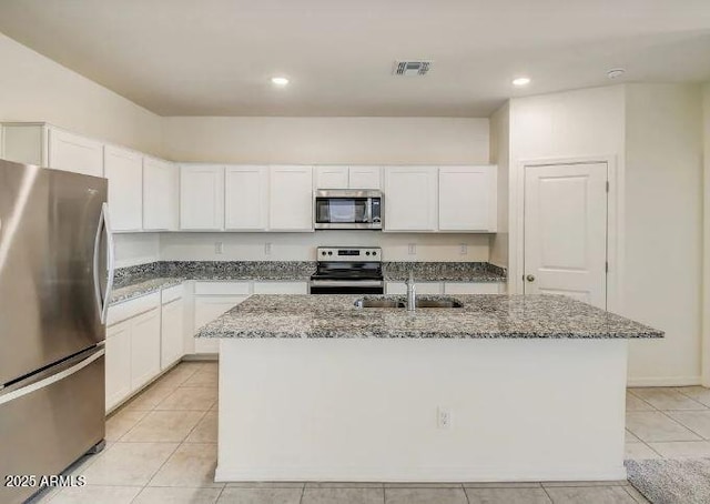 kitchen featuring a sink, dark stone countertops, an island with sink, and stainless steel appliances
