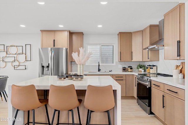 kitchen with sink, light brown cabinets, wall chimney exhaust hood, and appliances with stainless steel finishes