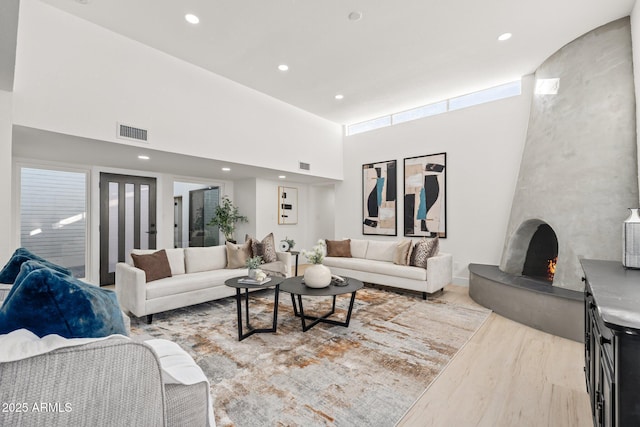 living room featuring a fireplace, a high ceiling, and light hardwood / wood-style flooring