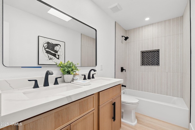 full bathroom featuring toilet, vanity, hardwood / wood-style floors, and tiled shower / bath