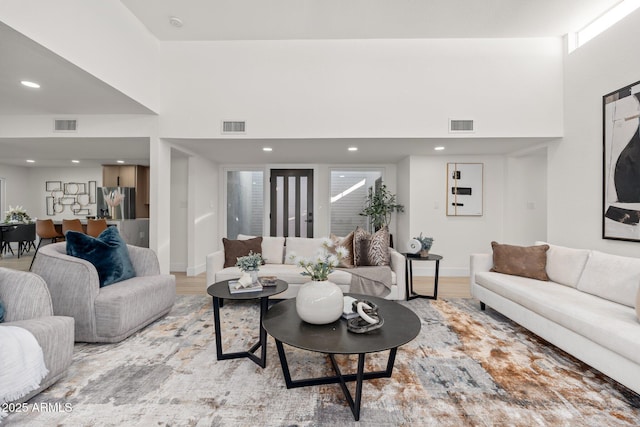 living room featuring a towering ceiling and light hardwood / wood-style flooring