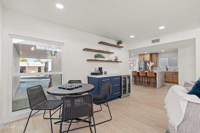 dining room featuring wine cooler, light hardwood / wood-style flooring, and sink