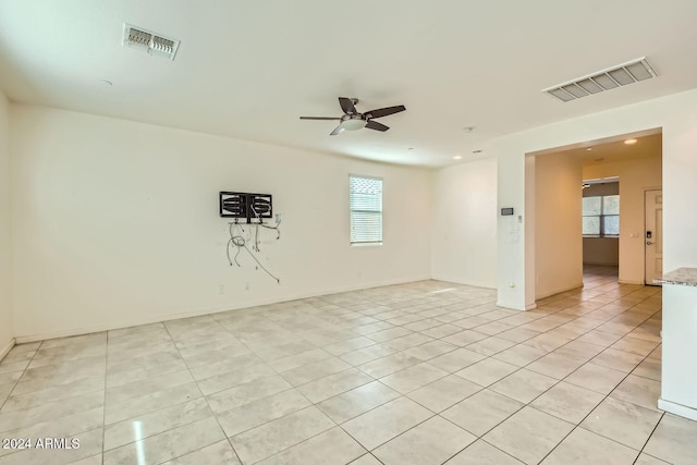 spare room featuring ceiling fan, light tile patterned floors, and a healthy amount of sunlight