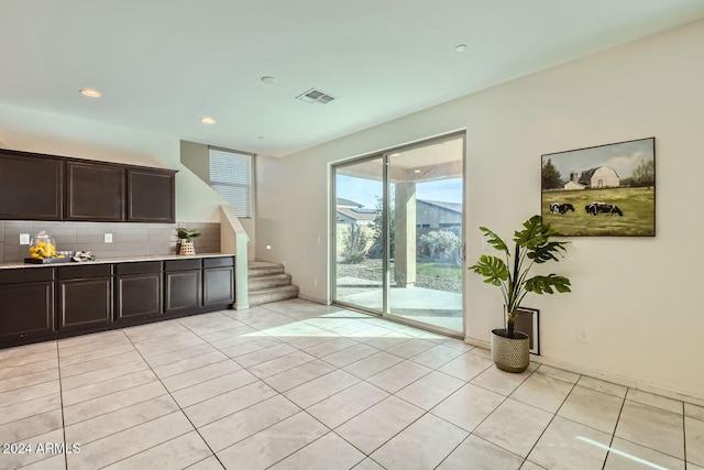 kitchen featuring backsplash, dark brown cabinetry, and light tile patterned flooring