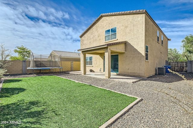 rear view of house with a lawn, cooling unit, a patio area, and a trampoline