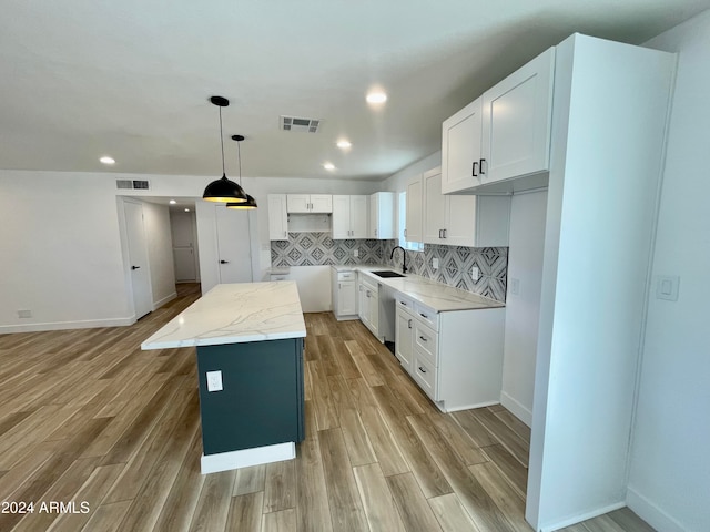 kitchen featuring white cabinetry, a center island, sink, hanging light fixtures, and light hardwood / wood-style flooring