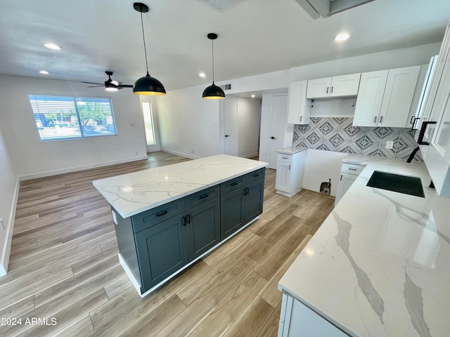 kitchen with pendant lighting, light hardwood / wood-style floors, light stone countertops, and white cabinetry